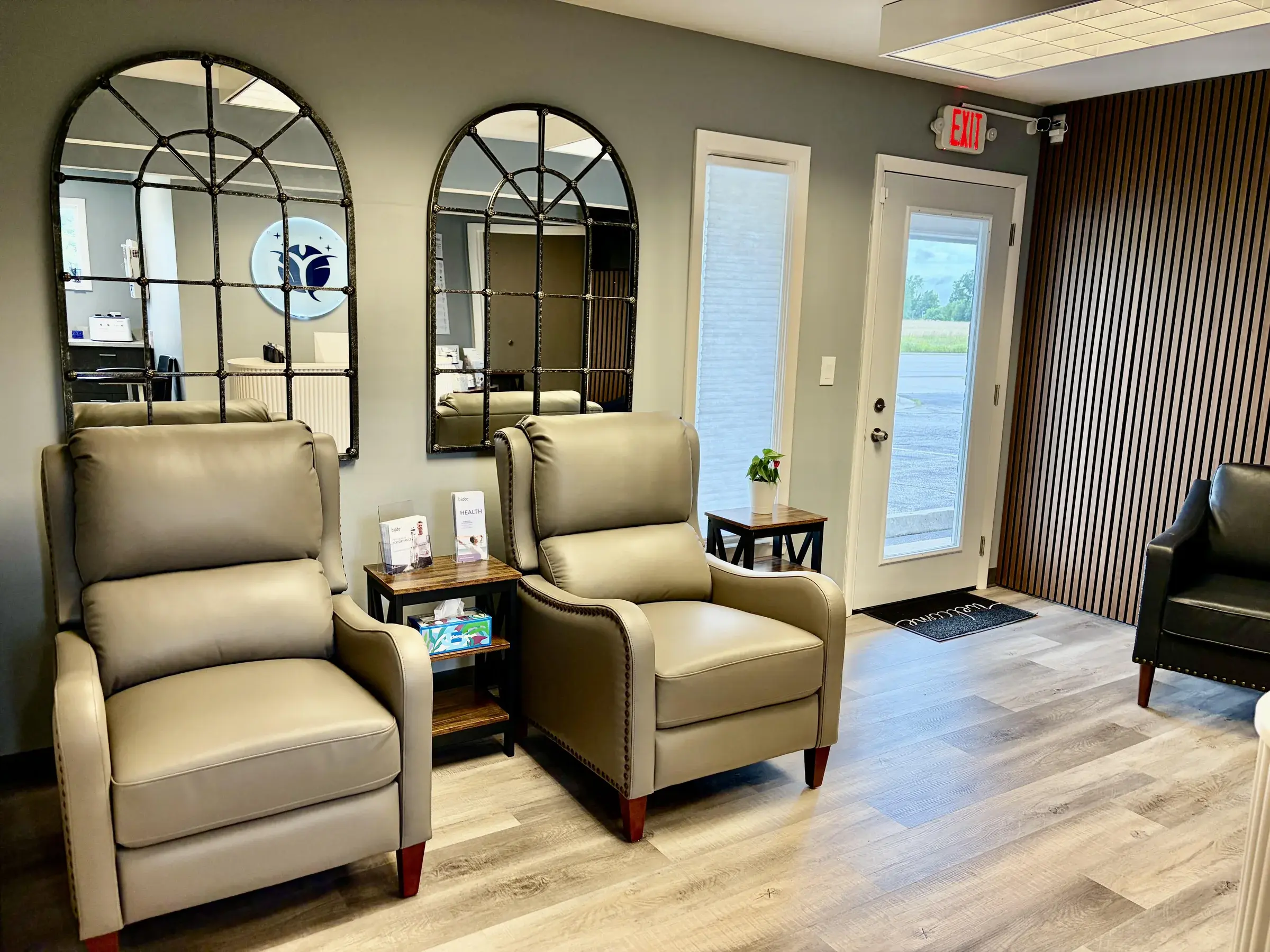 Stilwell Wellness Solutions waiting room with reclining chairs, arched mirrors, and a wood-accent wall.